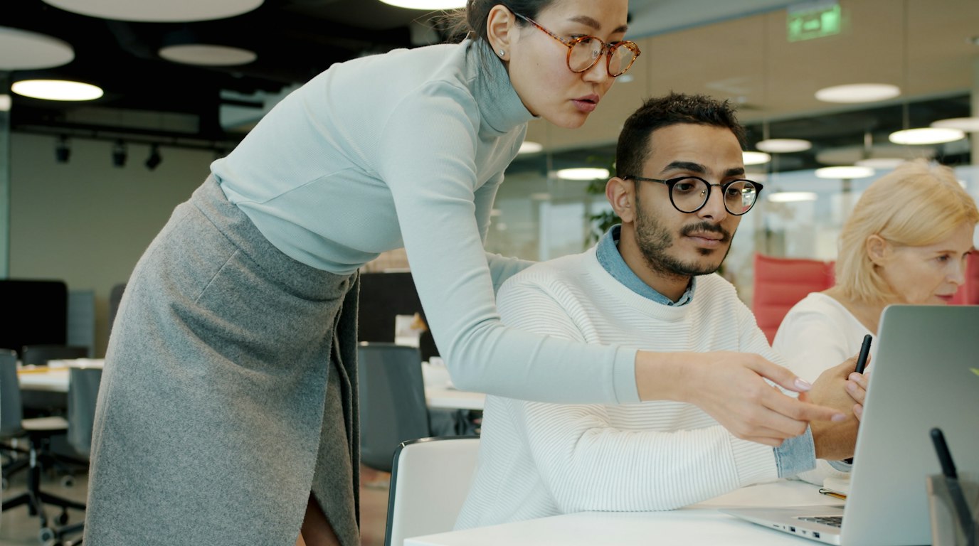 Two colleagues looking at a laptop together in an office