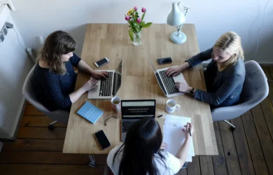 Three coworkers working on laptops at a shared office table