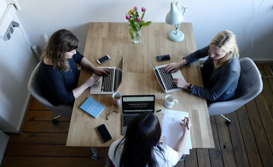 Three coworkers working on laptops at a shared office table