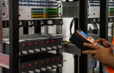 Technician in a high-visibility vest checking server rack equipment with a handheld diagnostic tool